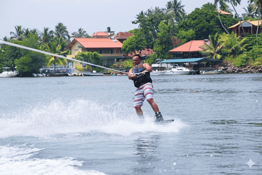 A person water skiing on a lake with houses and palm trees in the background. 3