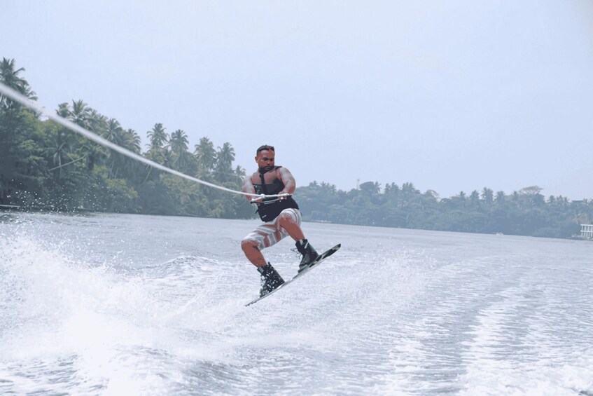 A person wakeboarding on a body of water with palm trees in the background. 2