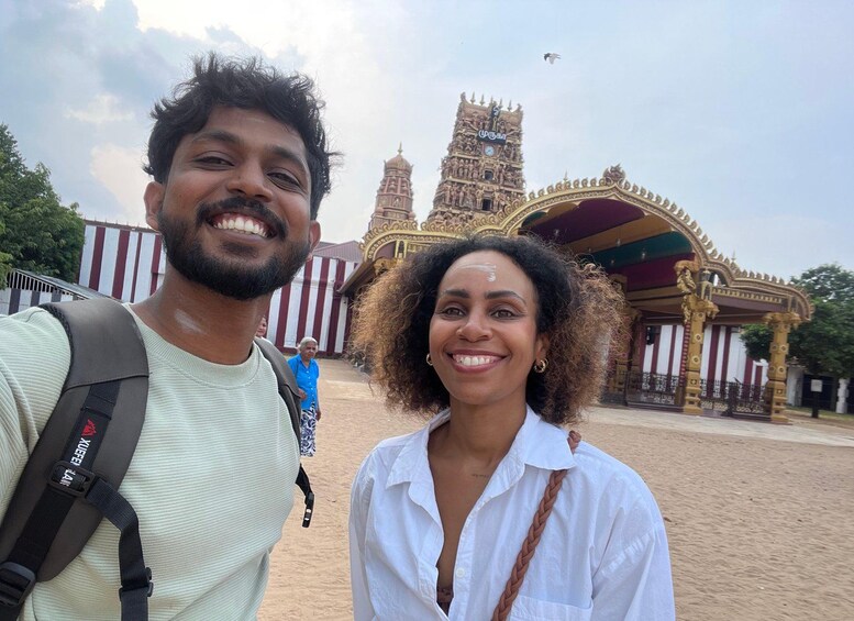 Two people in front of a temple with intricate architecture and a clock tower. 4
