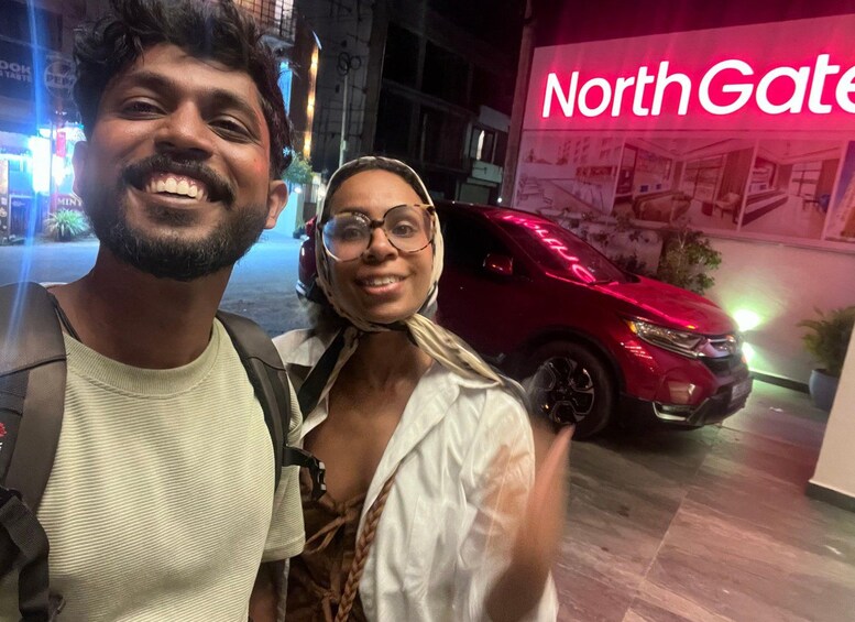 Two people standing in front of a red SUV with a 'NorthGate' sign in the background. 3