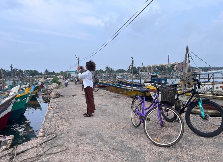 A person taking a photo, a bicycle, and boats at a harbor. 2