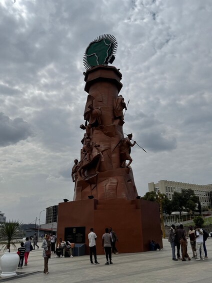 A large outdoor sculpture with multiple figures, a prominent circular top, and a base with inscriptions. 5