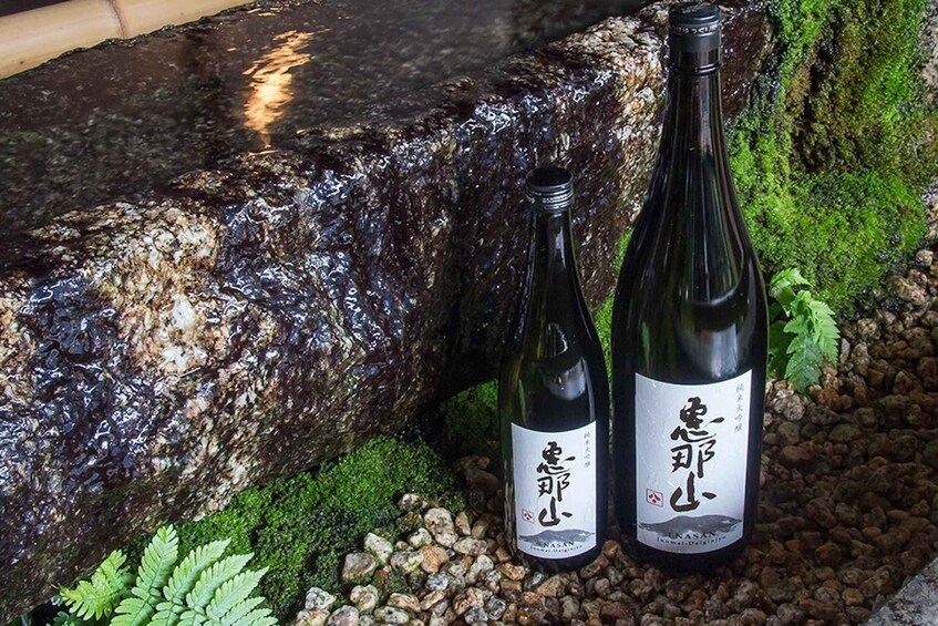 Two bottles of wine with labels in a natural setting with rocks and moss. 3