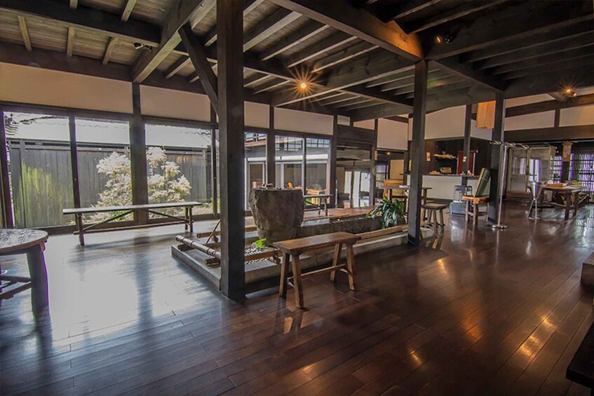 An indoor space with wooden flooring, large windows, and a stone feature. 4