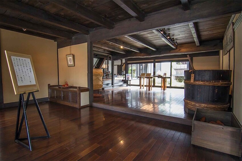 A spacious room with wooden floors, a whiteboard, and a rustic barrel. 2