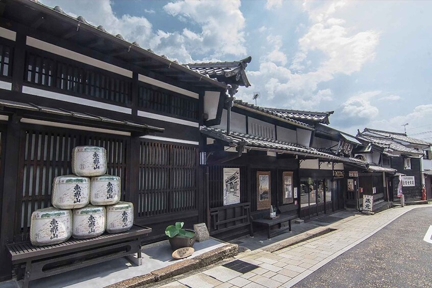 A traditional Japanese building with a tiled roof and wooden walls, a display of packaged goods, and a clear sky. 1