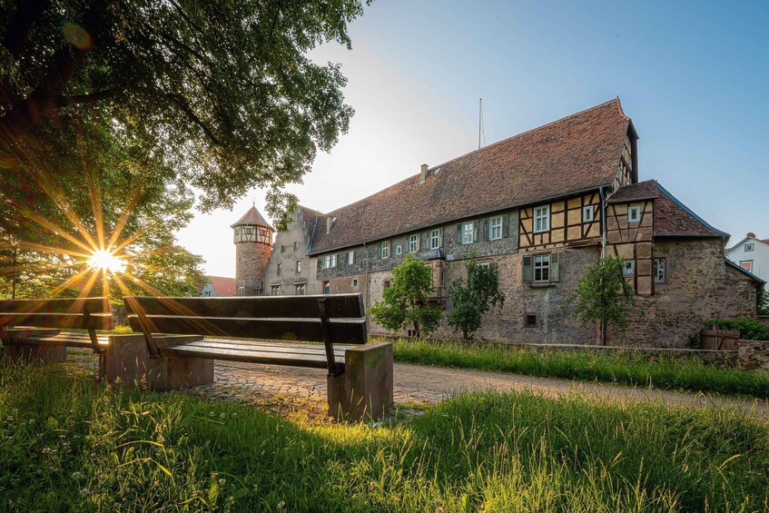 A historic building with a tower, surrounded by lush greenery and a cobblestone path. 2