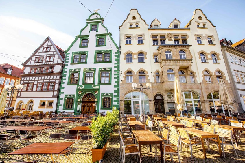 A cobblestone square with outdoor seating and historic buildings with green and white facades. 3