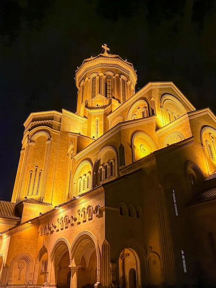 A large, illuminated cathedral with a prominent dome and cross, featuring intricate architectural details and arched windows. 2
