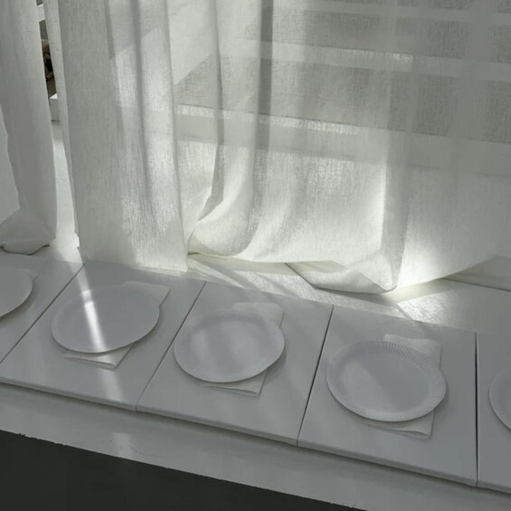 A window with white curtains and four paper plates on a white ledge. 5
