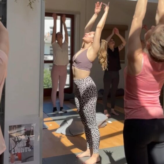 A yoga class in a room with a poster of yoga events. 1