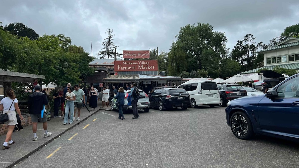 A crowded farmers' market with a banner celebrating 20 years. 1