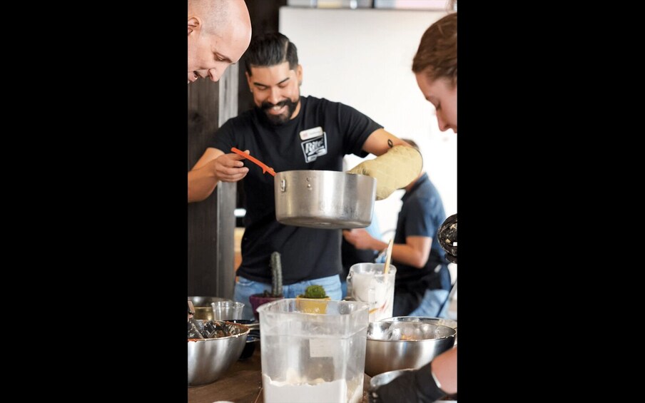 A person cooking, with a pot and a ladle, in a kitchen setting. 3