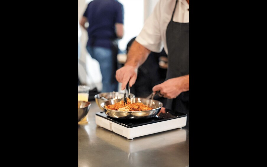 A person cooking on a portable stove with a pan of food. 4