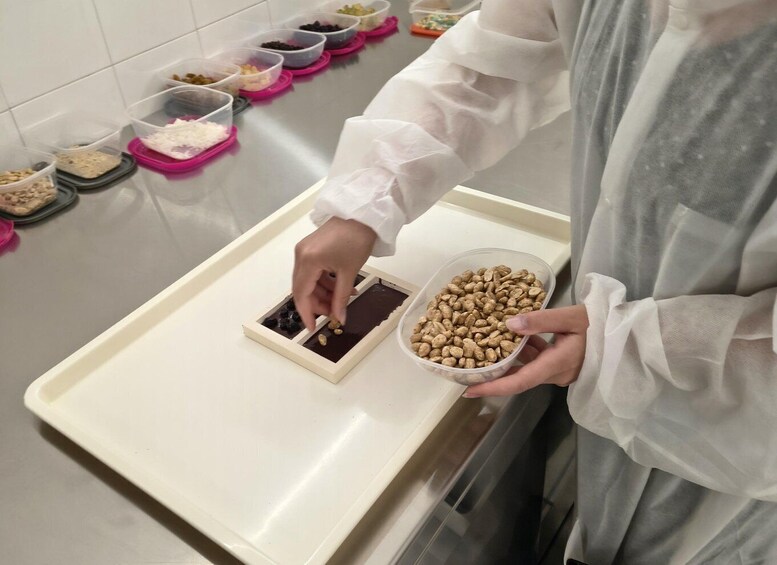 A person holding a container of peanuts and a tray with various food items. 3