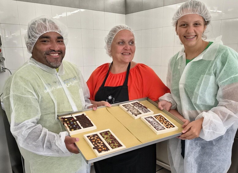 Three people in a kitchen holding a tray with various food items. 5