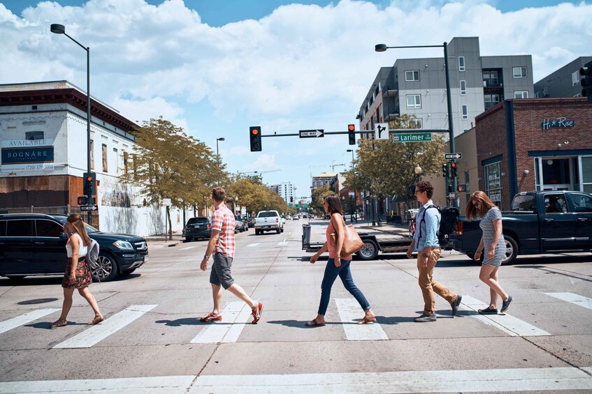 A crosswalk with pedestrians, a traffic light, and buildings in the background. 4