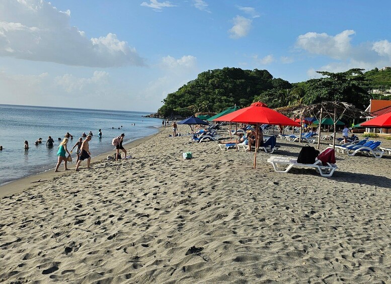A beach with people swimming and sunbathing under umbrellas. 3
