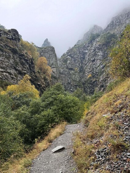 A narrow mountain path surrounded by rocky cliffs and autumn foliage. 4