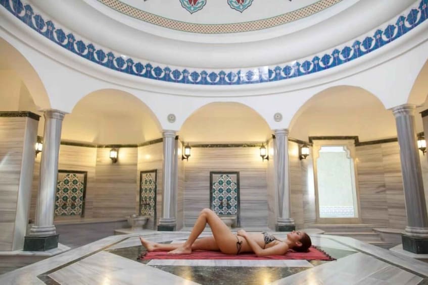 A person lying on a mat in a room with arches and patterned walls. 2