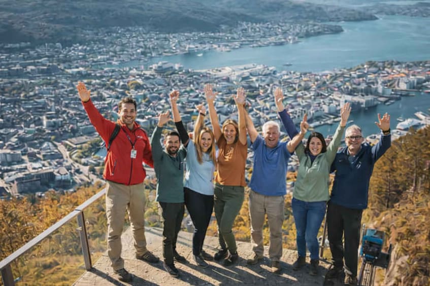 A group of people on a viewing platform overlooking a coastal cityscape with boats and a harbor. 1