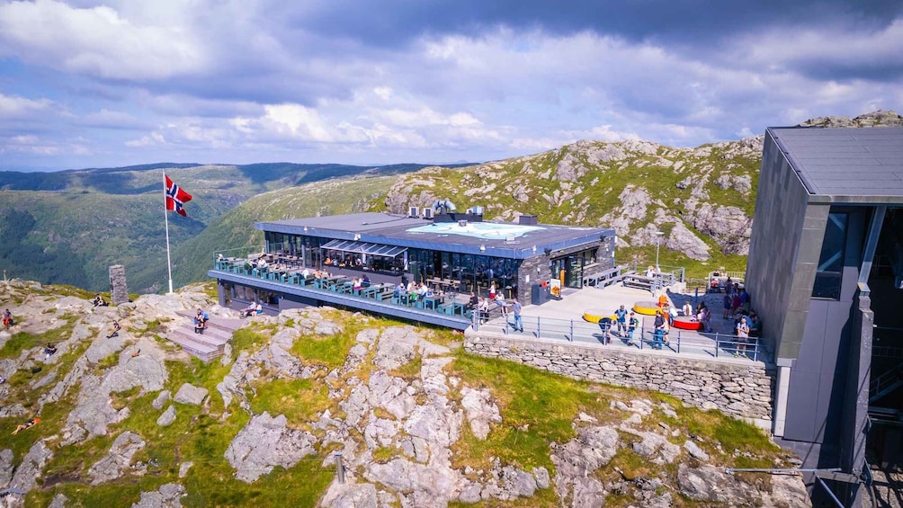 A mountain observation deck with visitors, a flag, and a rocky landscape. 2