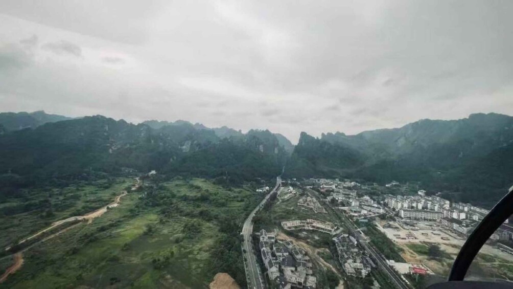 A mountainous landscape with a winding road, a small settlement, and a bridge. 4