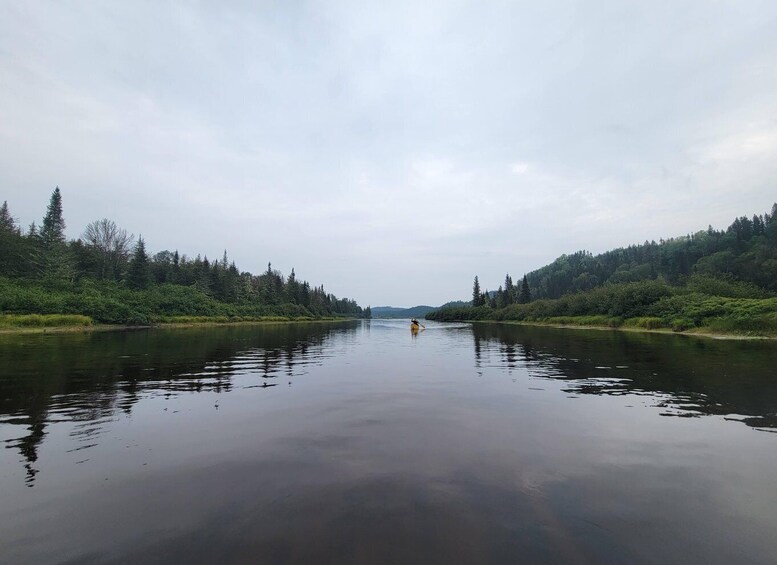 A calm river flanked by dense forests under a cloudy sky. 3