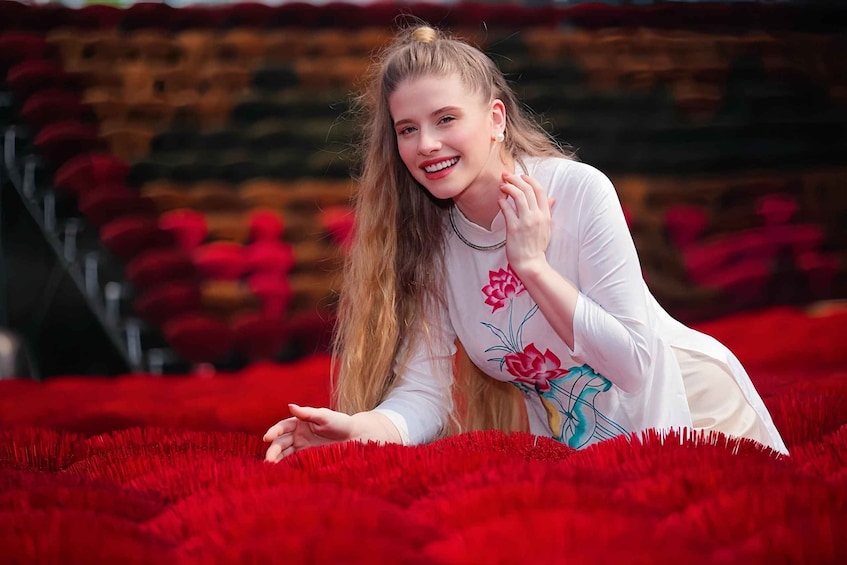 A person lying on red carpet-like flooring with a floral design, in an outdoor setting with a blurred background. 1