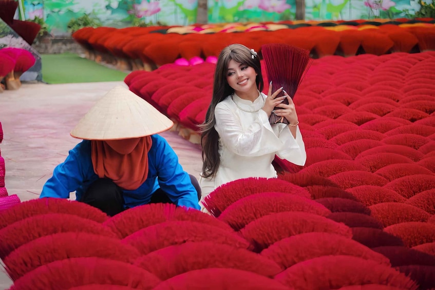 A person in a blue outfit and a conical hat working among red plants. 3