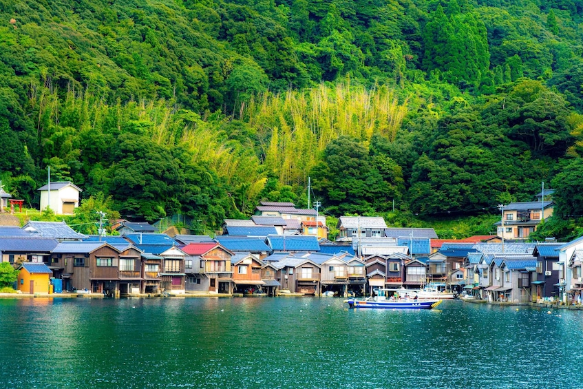 A riverside village with traditional wooden houses and a boat docked in the water. 2