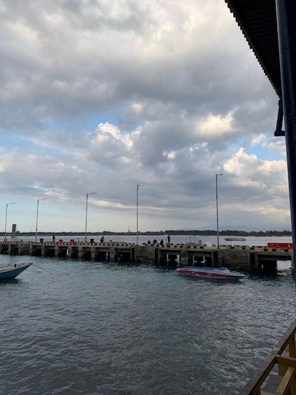 A pier with boats, a cloudy sky, and a distant shoreline. 2