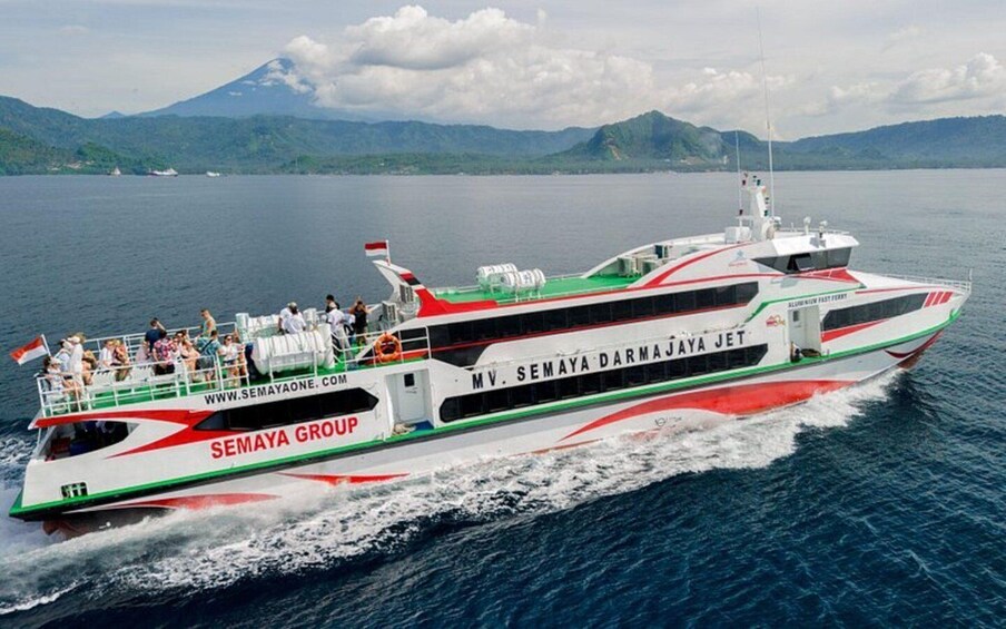 MV Semaya Darma Jaya Jet, a ferry with passengers, sailing on a calm sea with mountains in the background. 1