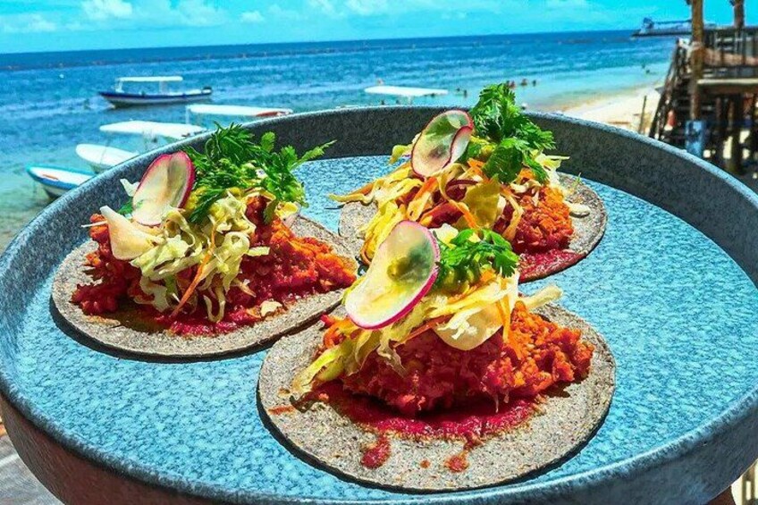 A seafood dish on a blue plate with a beach and ocean in the background. 1
