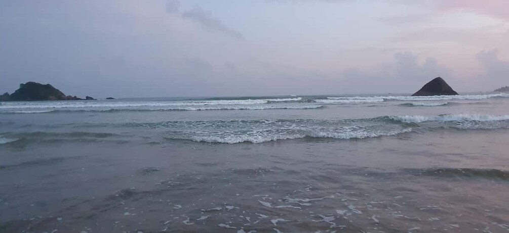 A beach with waves, a distant island, and a cloudy sky. 5