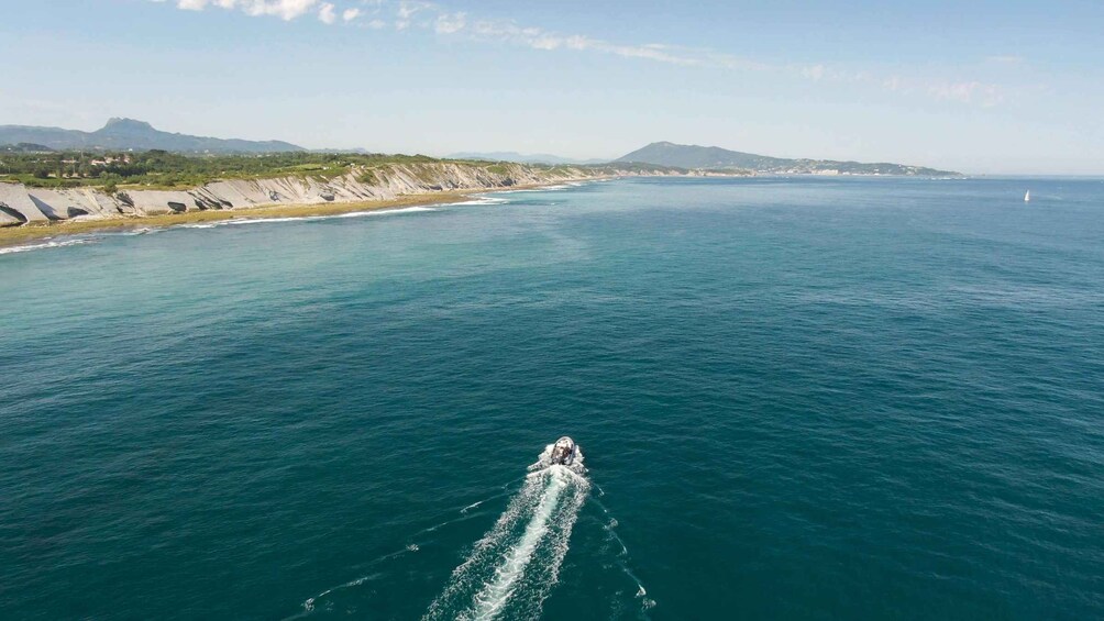 A boat moving across a calm sea with a coastline in the background. 2