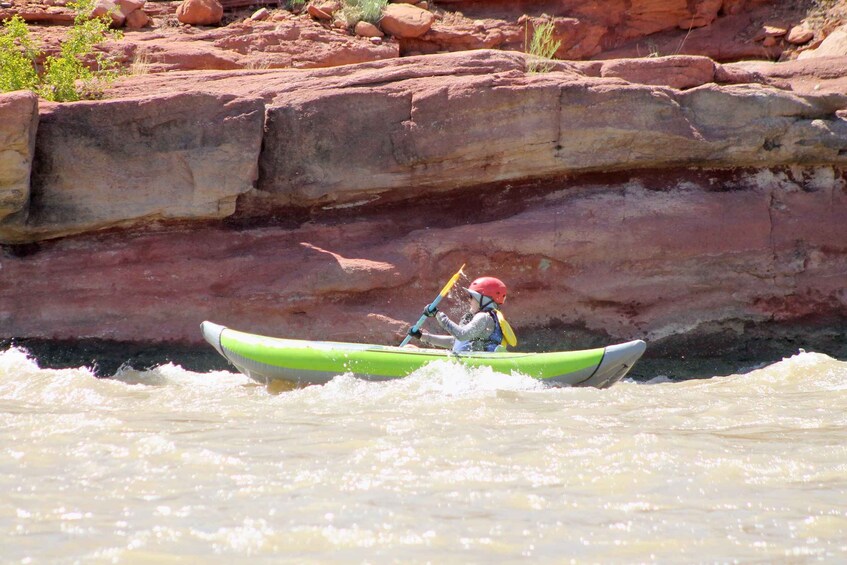 A person kayaking on a river with red rock formations in the background. 2