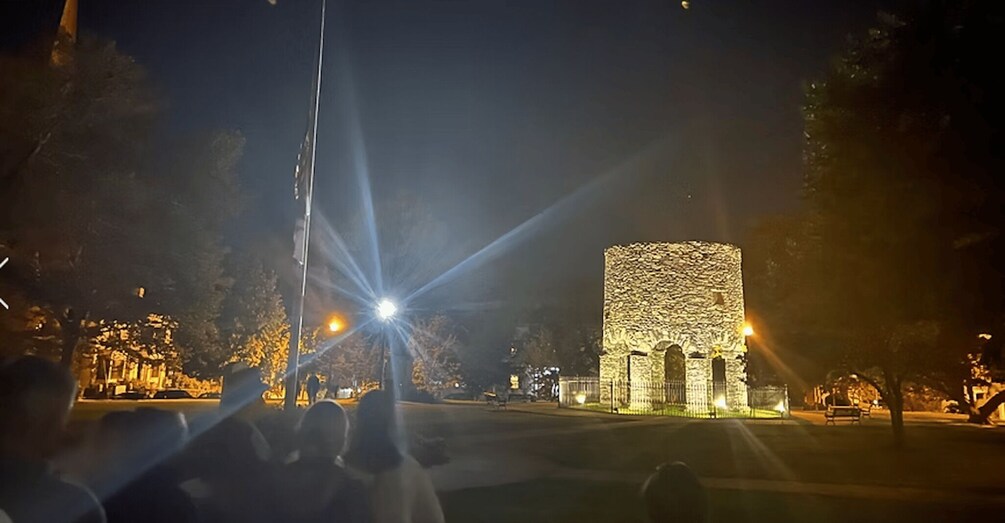 A stone structure illuminated at night with a street in the foreground. 4