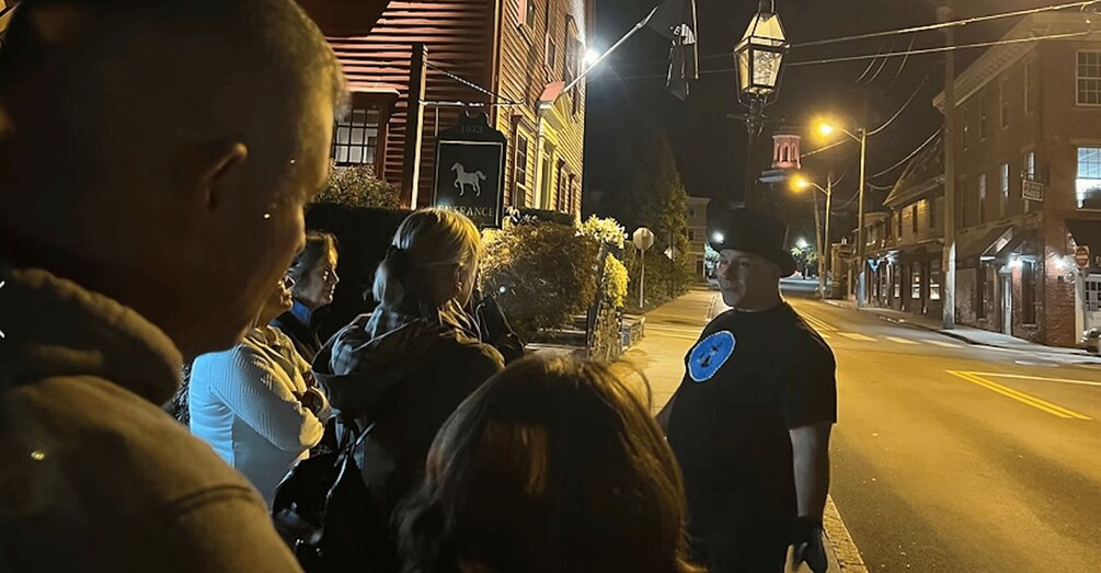 A nighttime street scene with a group of people gathered, a police officer with a badge, and buildings with illuminated windows. 5