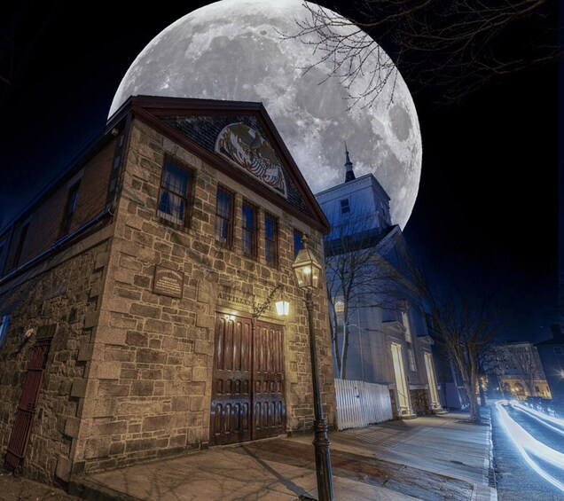 A historic stone building with a large moon in the background. 1