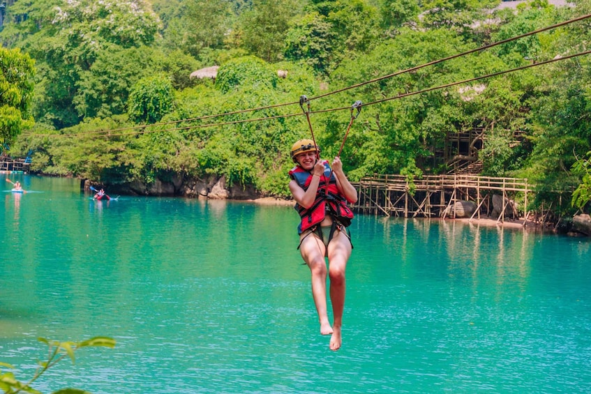 A person zip-lining over a turquoise river with lush greenery in the background. 4