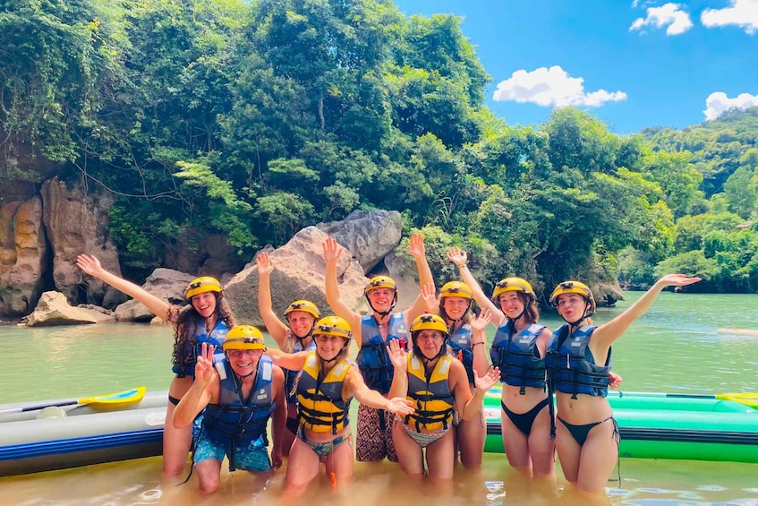 A group of people in a raft on a river surrounded by greenery. 1
