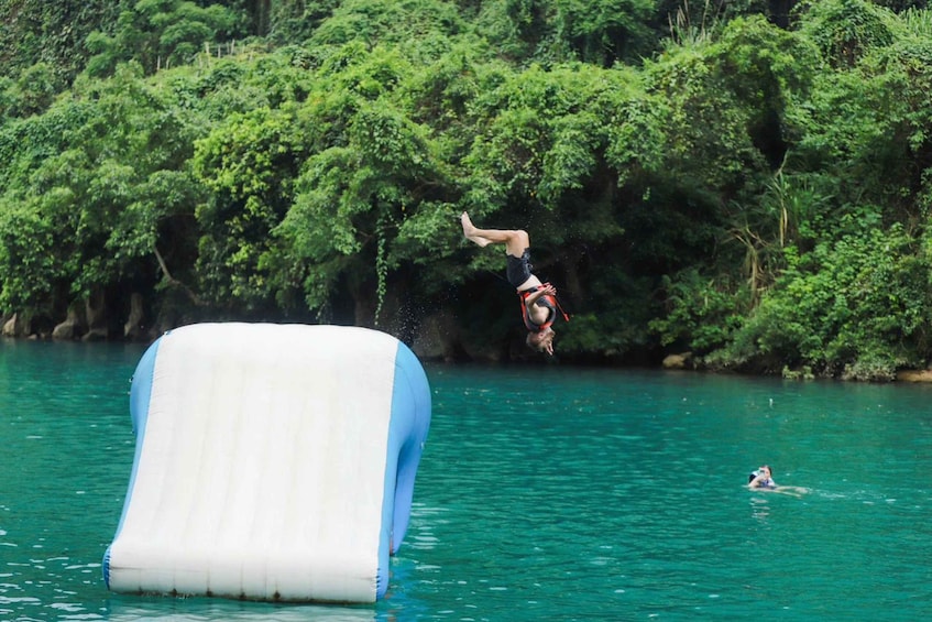 A person performing a backflip off a water slide in a natural setting. 5