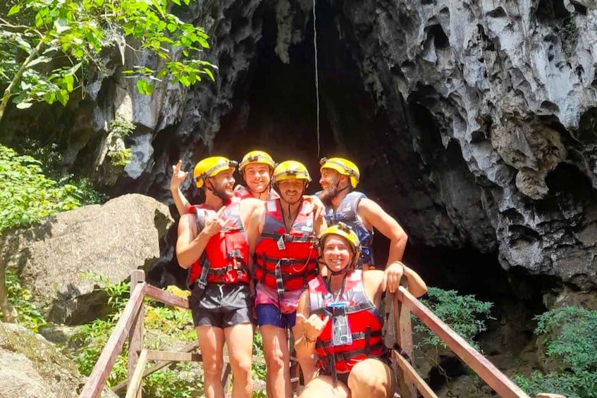 A group of people in helmets and life vests at the entrance of a cave. 2