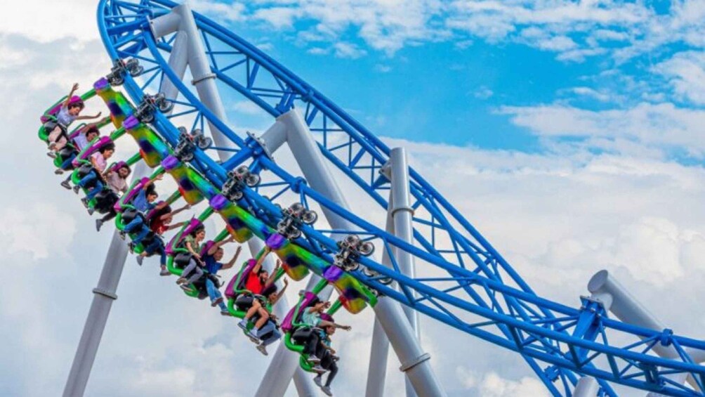 A roller coaster in motion with riders seated in colorful cars. 1