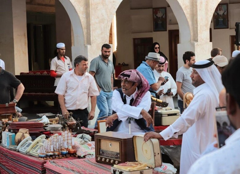 A group of people in traditional attire at a market stall with various items for sale. 5