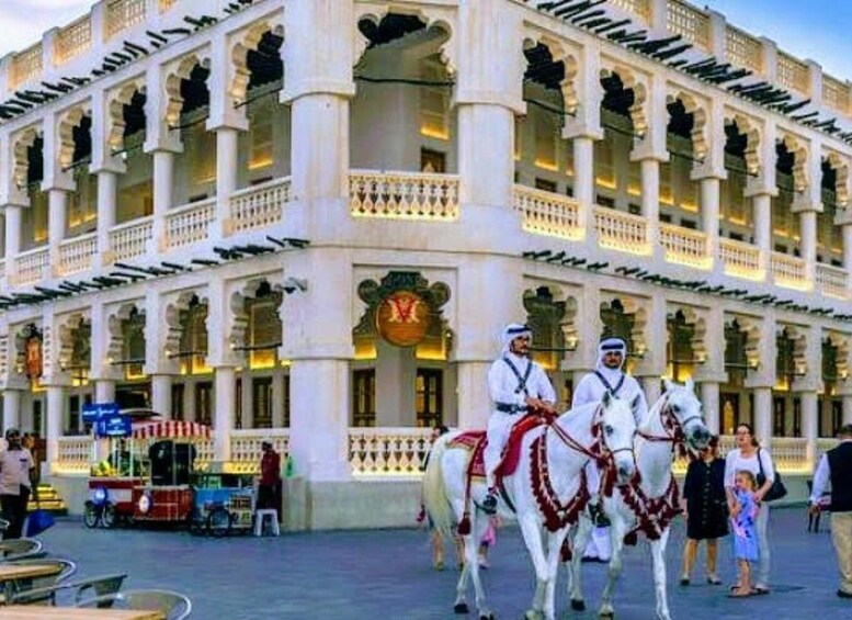 A historic building with multiple arches and columns, a clock, and a group of guards on horseback. 4