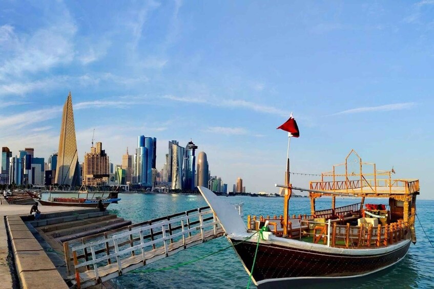 A traditional boat docked at a pier with a modern city skyline in the background. 1