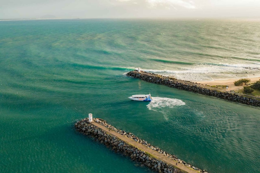 A boat on a calm sea, a rocky breakwater, and a lighthouse. 5
