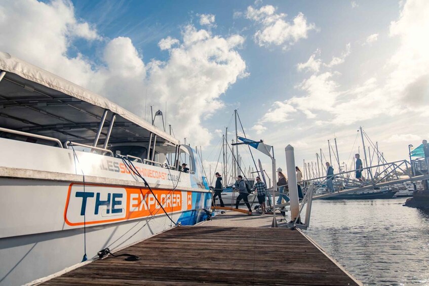 A dock with a boat named 'THE EXPLORER' and people walking on the wooden pier. 4